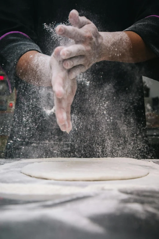 a person is sprinkling flour on a pizza, inspired by Chippy, trending on unsplash, process art, hands shielding face, in a workshop, wok, round-cropped