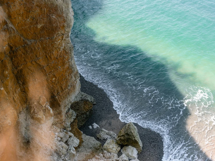 a man standing on top of a cliff next to the ocean, by Daren Bader, pexels contest winner, dark green water, normandy, middle close up composition, thumbnail