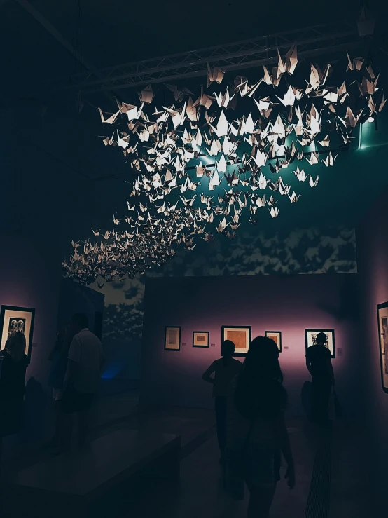 a group of people standing in a dark room, origami crane drawings, magical atmosphere + masterpiece, trending on vsco, exhibition