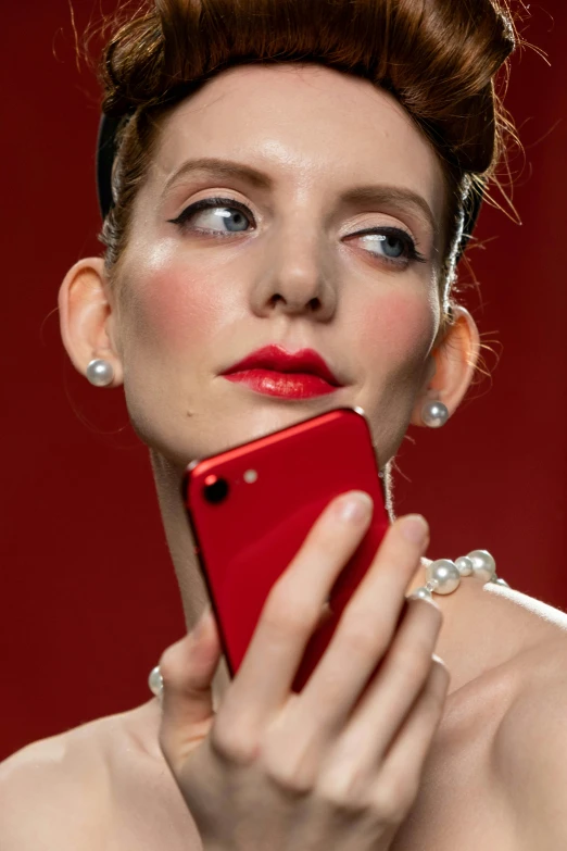 a woman holding a cell phone up to her face, by Paul Bird, trending on pexels, magic realism, pearl earring, all red, anna kendrick, dior campaign