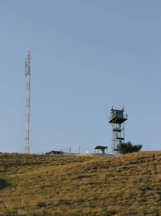 a tall tower sitting on top of a grass covered hillside, radio equipment, softair center landscape, screens, promo image