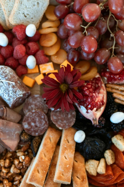 a platter of cheese, crackers, fruit and nuts, crimson themed, edible flowers, up-close, religious