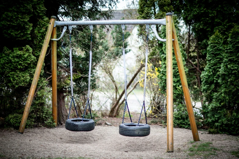 a couple of tires sitting on top of a wooden swing, by Peter Churcher, unsplash, activity play centre, garner holt, grey, garden