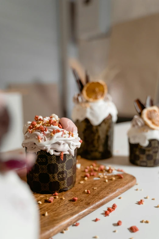 a couple of cupcakes sitting on top of a wooden cutting board, a picture, by Julia Pishtar, trending on pexels, renaissance, ice cream cones, copper cup, fine dining, profile image