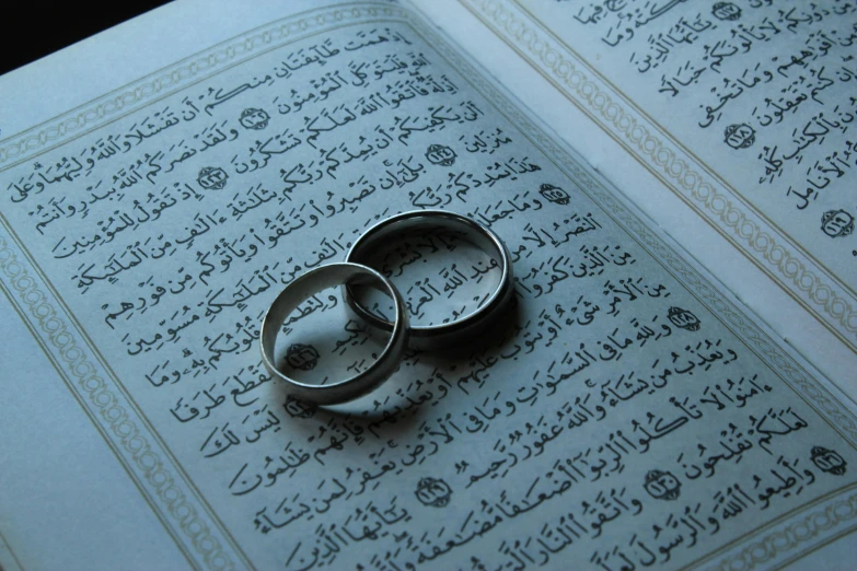 two wedding rings sitting on top of an open book, hurufiyya, instagram picture, ap, contain, middle eastern