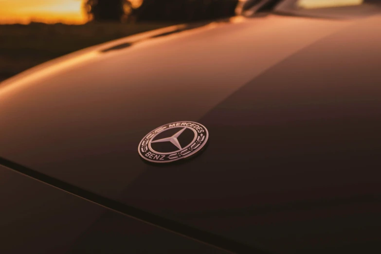 a close up of a badge on the hood of a car, by Niko Henrichon, pexels contest winner, symbolism, mercedez benz, late summer evening, die cut sticker, black car