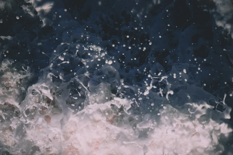 a person riding a surfboard on top of a wave, an album cover, inspired by Elsa Bleda, trending on unsplash, conceptual art, water particles, dark blue water, background image, foamy bubbles