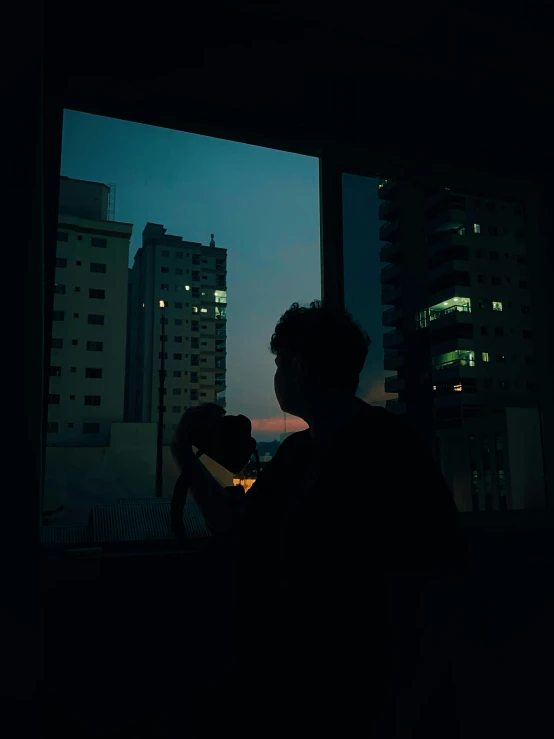 a man looking out a window at a city at night, inspired by Elsa Bleda, unsplash contest winner, silhouette!!!, lofi portrait, instagram photo, shot with hasselblad