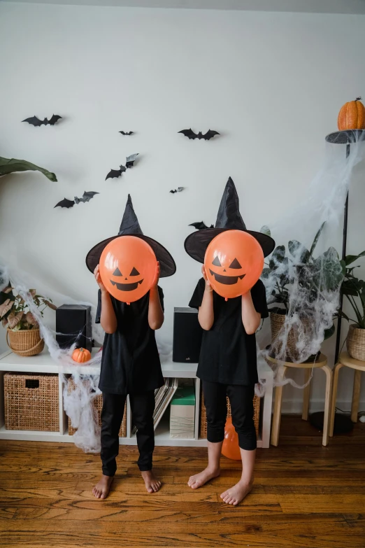 a couple of kids standing on top of a wooden floor, halloween decorations, gen z, ( ( ( black witch hat ) ) ) ), baloons