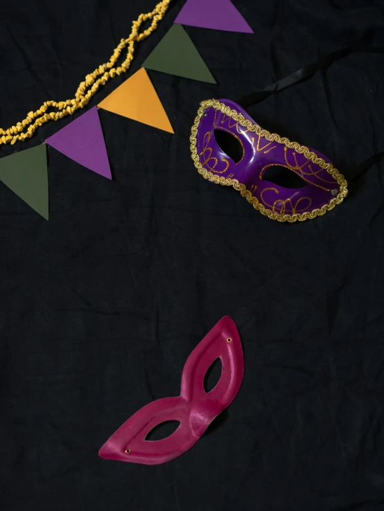 a couple of masks sitting on top of a table, by Carey Morris, trending on unsplash, ((purple)), celebration costume, black and yellow and red scheme, a high angle shot