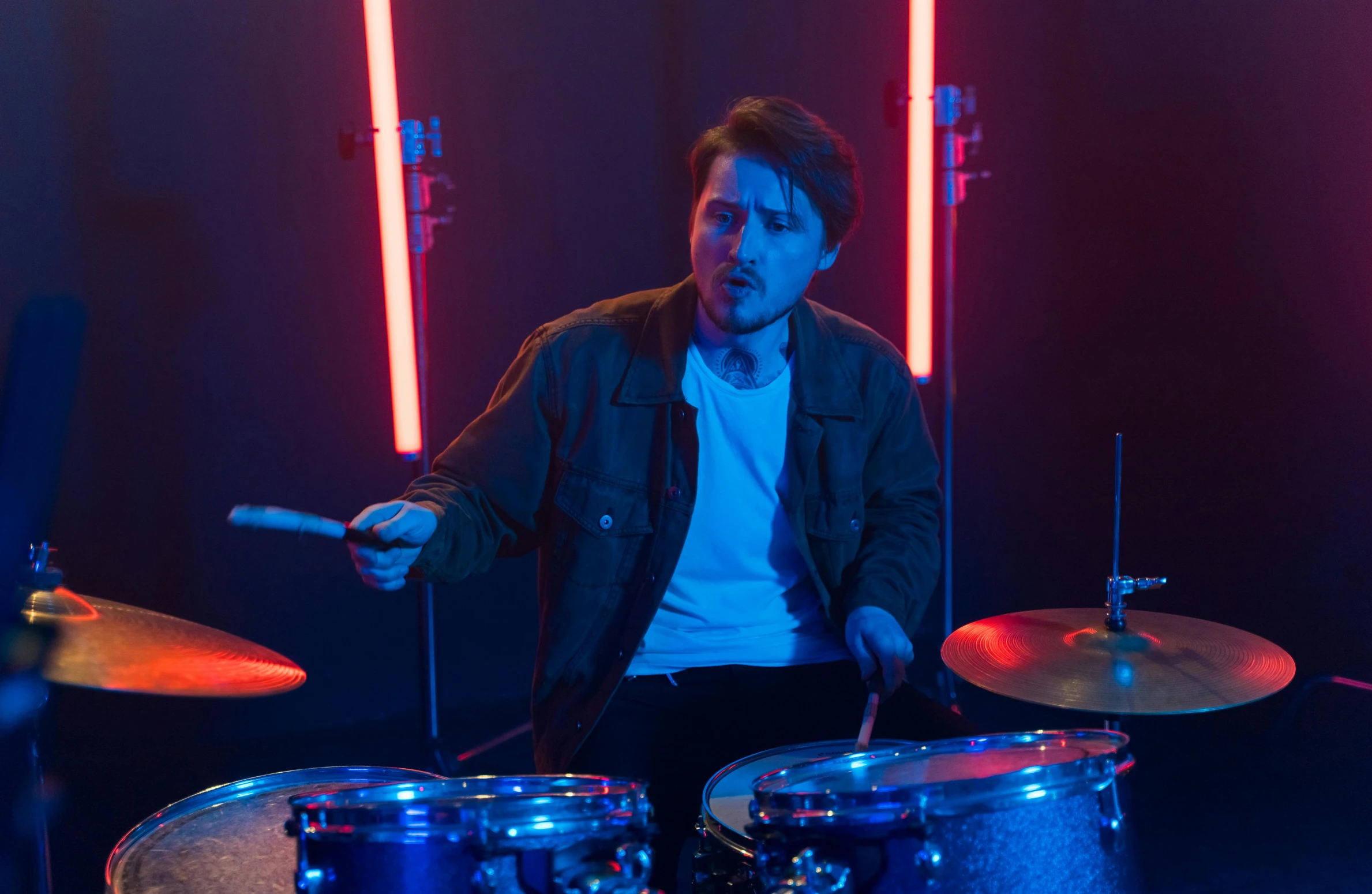 a man sitting in front of a drum set, cinematic neon uplighting, mark edward fischbach, cinematic accent lighting, promo image