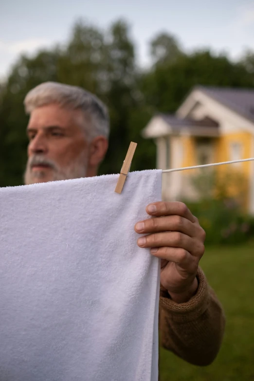 a man holding a white towel on a clothes line, an album cover, inspired by Albert Anker, pexels contest winner, photorealism, people looking at a house, 15081959 21121991 01012000 4k, old man, summer evening