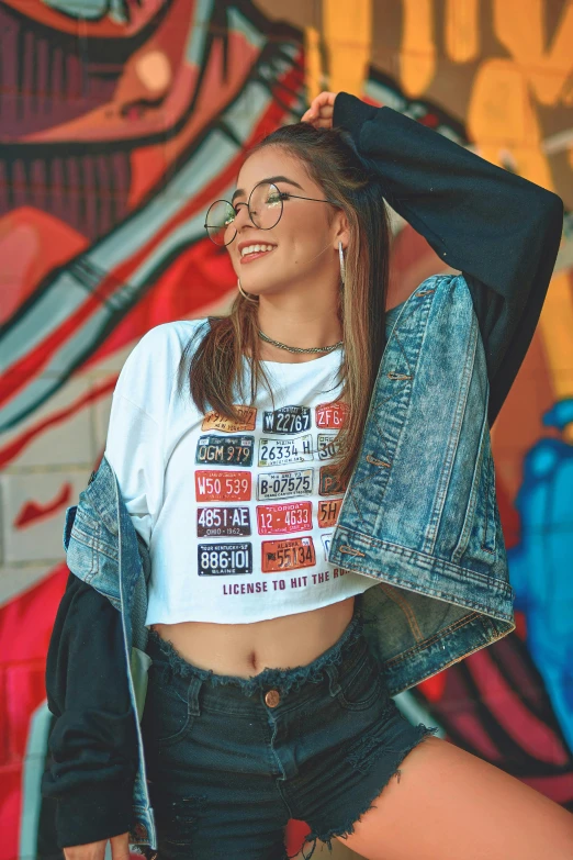 a woman standing in front of a graffiti wall, a cartoon, trending on pexels, with ripped crop t - shirt, cropped shirt with jacket, 15081959 21121991 01012000 4k, smiling fashion model