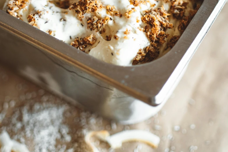 a pan of ice cream sitting on top of a wooden table, trending on unsplash, seeds, detailed product image, epicurious, cake