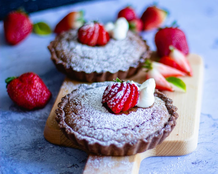 a couple of desserts sitting on top of a wooden cutting board, profile image