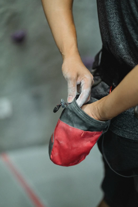 a close up of a person holding a pair of shoes, belaying, red gloves, pouches, soft surfaces