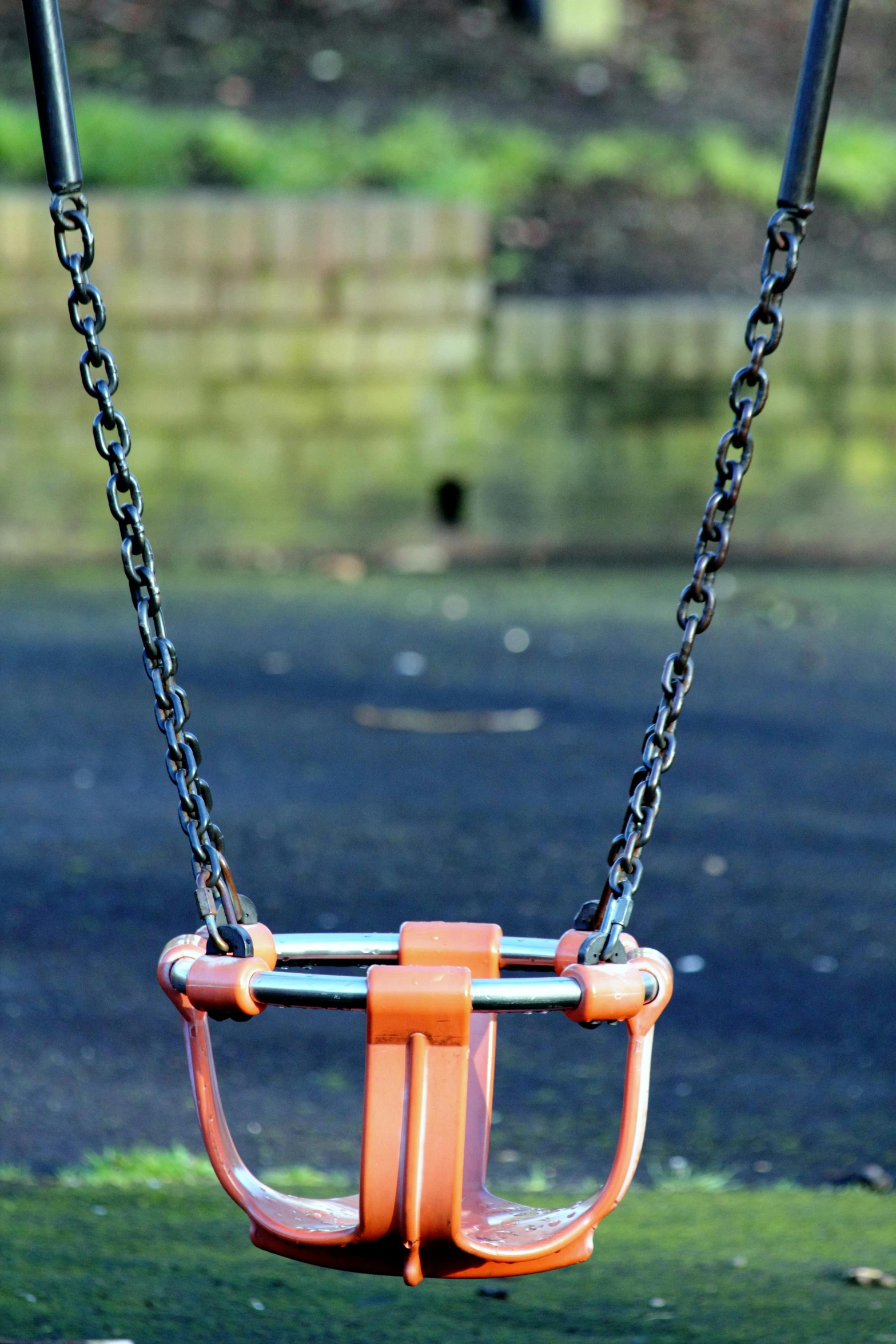 a close up of a swing at a park, by Ian Fairweather, ((chains)), orange metal ears, dark. no text, play