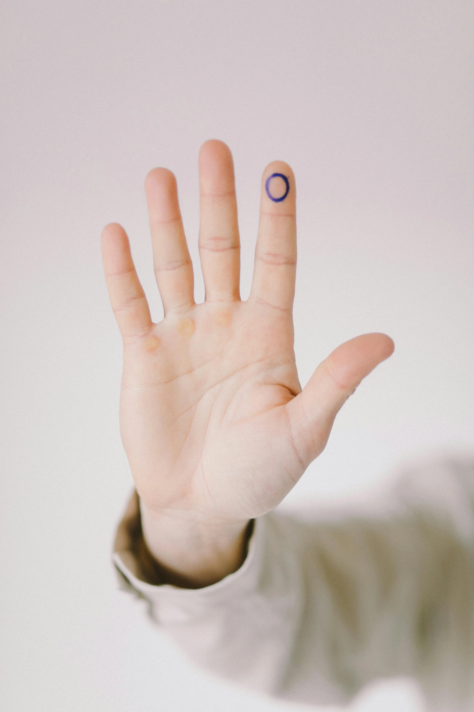 a person holding their hand up with a smiley face painted on it, by Olivia Peguero, aestheticism, cyber augmentation implant, blue ink, minimalist rule of thirds, wearing a patch over one eye