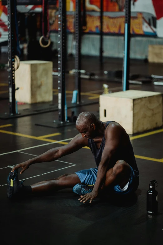 a man sitting on the ground in a gym, pexels contest winner, hyperrealism, man is with black skin, pixeled stretching, thumbnail, hydration