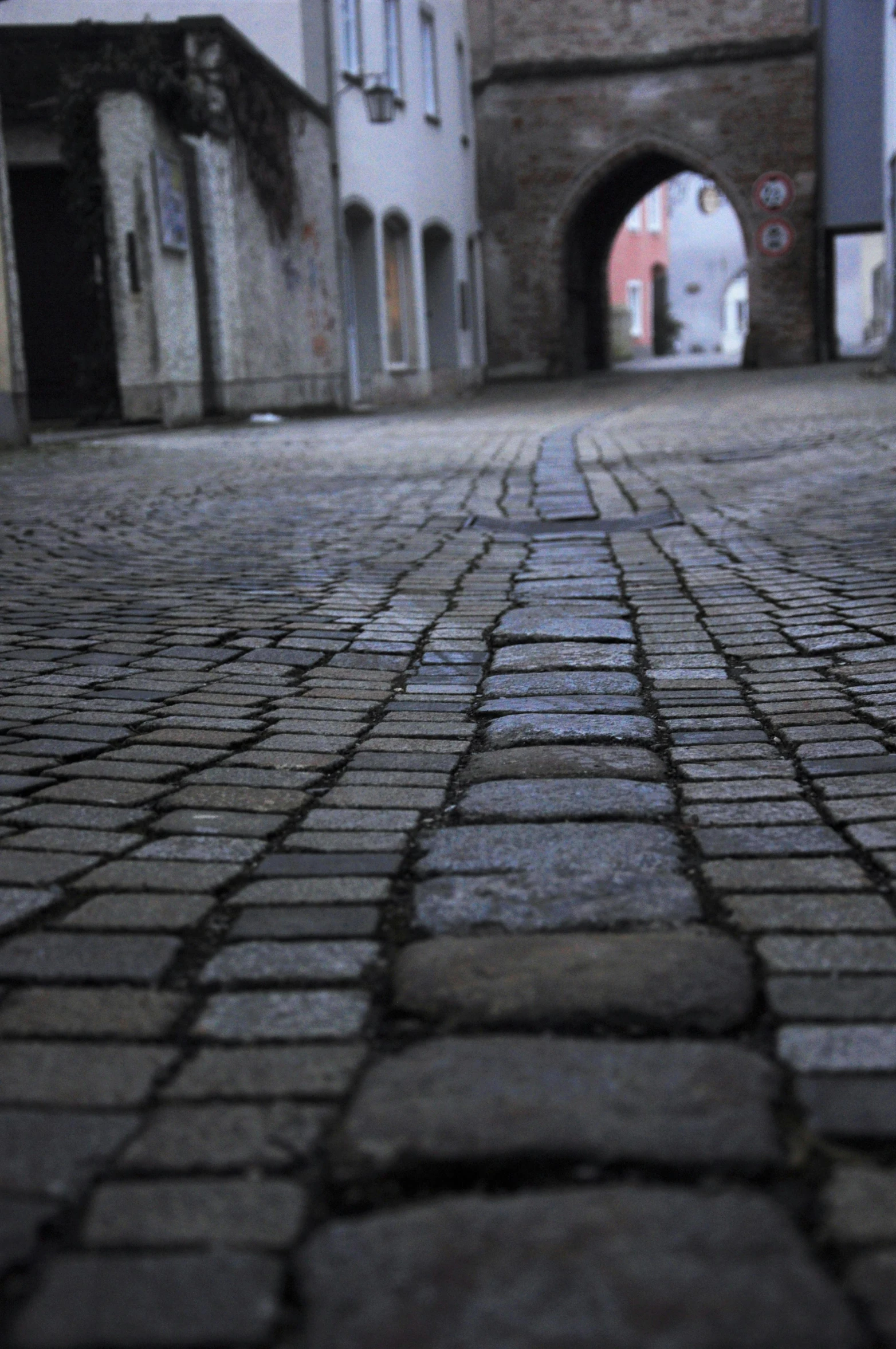 a black and white photo of a cobblestone street, an album cover, by Anna Haifisch, happening, a ghetto in germany, close-up!!!!!, low angle!!!!, 2 4 mm iso 8 0 0 color