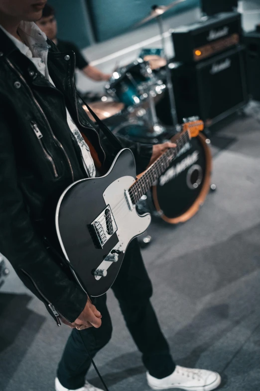 a man playing a guitar in a recording studio, by Robbie Trevino, trending on pexels, modernism, wearing a leather jacket, holding a silver electric guitar, a person at a music festival, profile image
