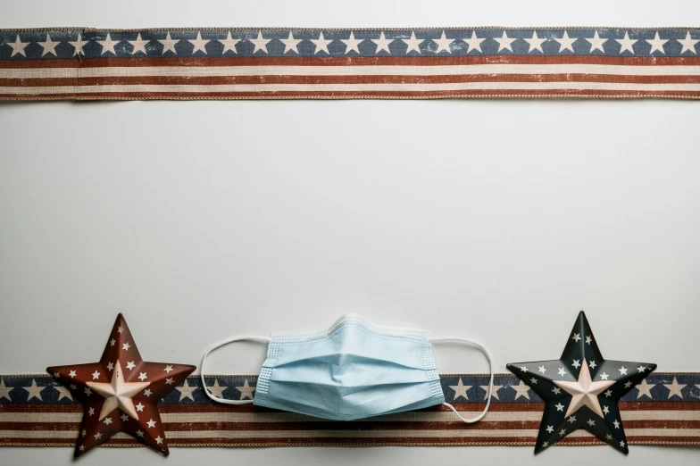 three stars and a face mask hanging on a wall, by Carey Morris, pexels, fourth of july, on a white table, surgical supplies, background image