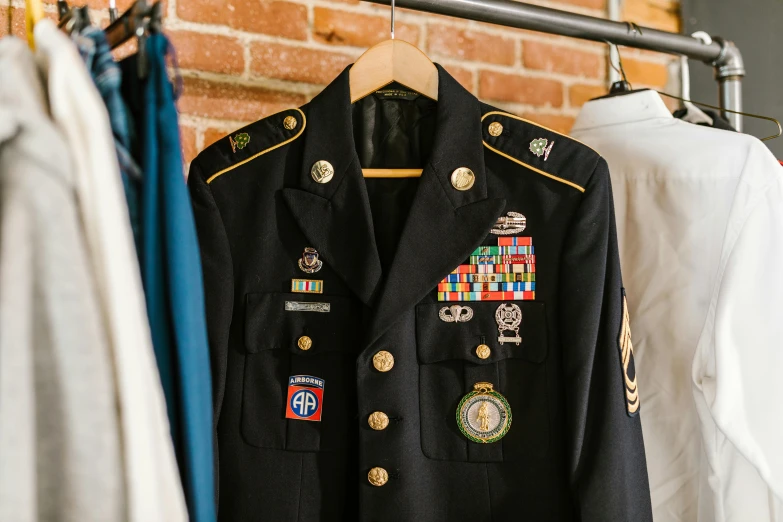 a suit on a hanger in front of a brick wall, wearing military uniform, military flags, in black uniform, award - winning details