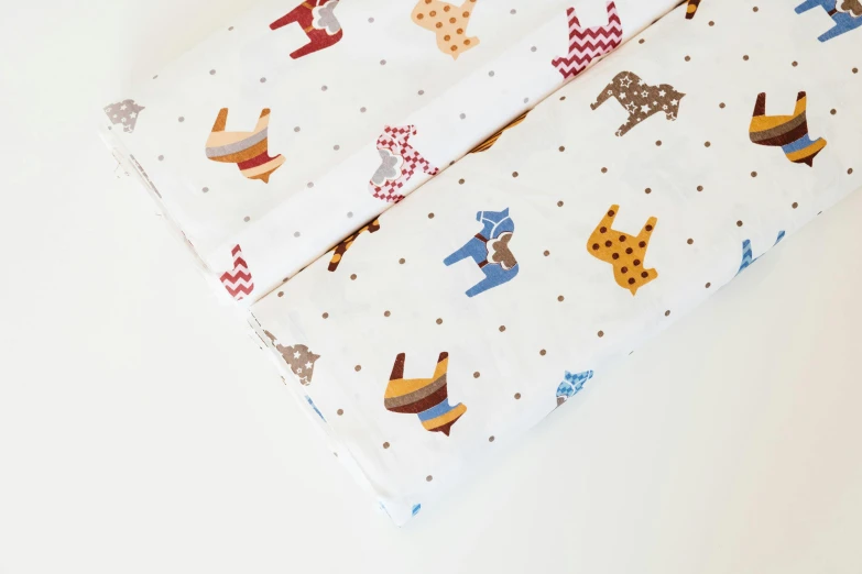 a close up of a folded sheet on a table, by Emma Andijewska, folk art, camels, white background, polka dot, product shot