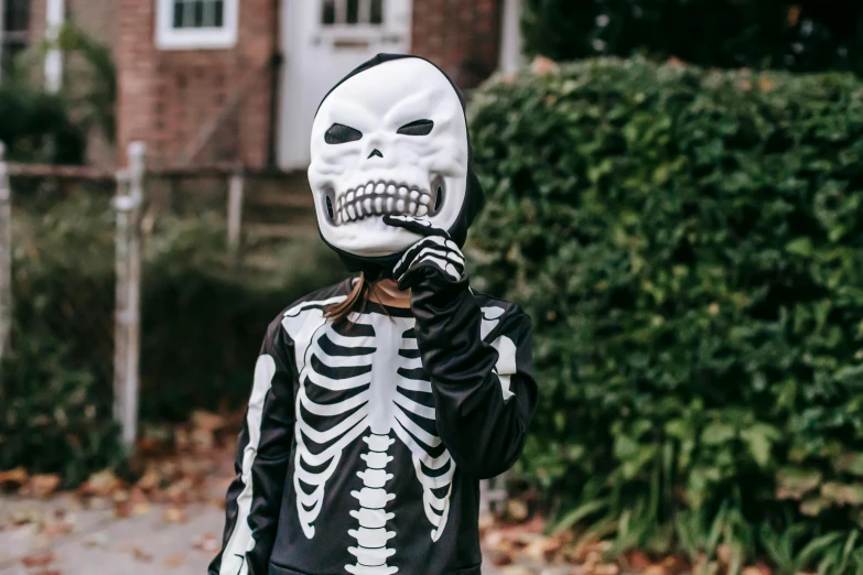 a little girl dressed up in a skeleton costume, a cartoon, by Emma Andijewska, pexels, balaclava, instagram picture, sans, closed mouth showing no teeth