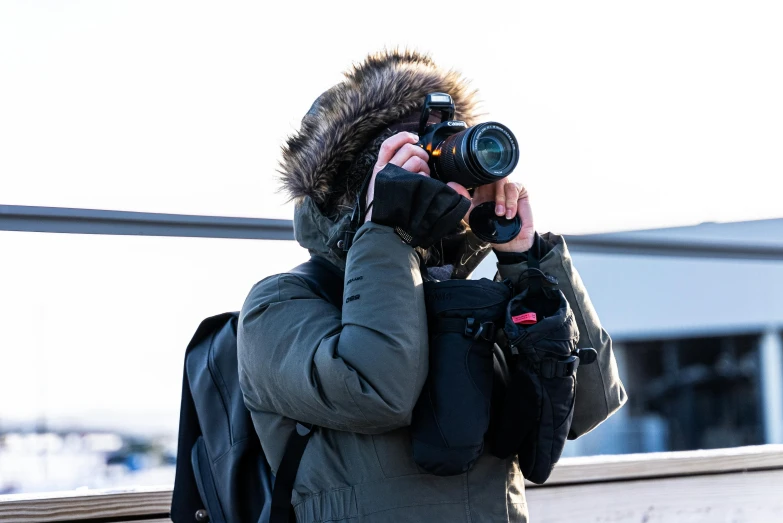 a person taking a picture with a camera, by Ejnar Nielsen, happening, reykjavik, over the shoulder shot, winter photograph, cinematic outfit photo