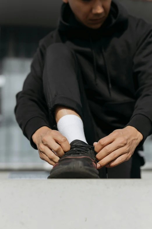 a man sitting on a ledge tying his shoe, all black matte product, compression, ilustration, about to step on you