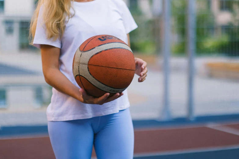 a woman holding a basketball on a court, dressed in a white t shirt, less detailing, feature, background image