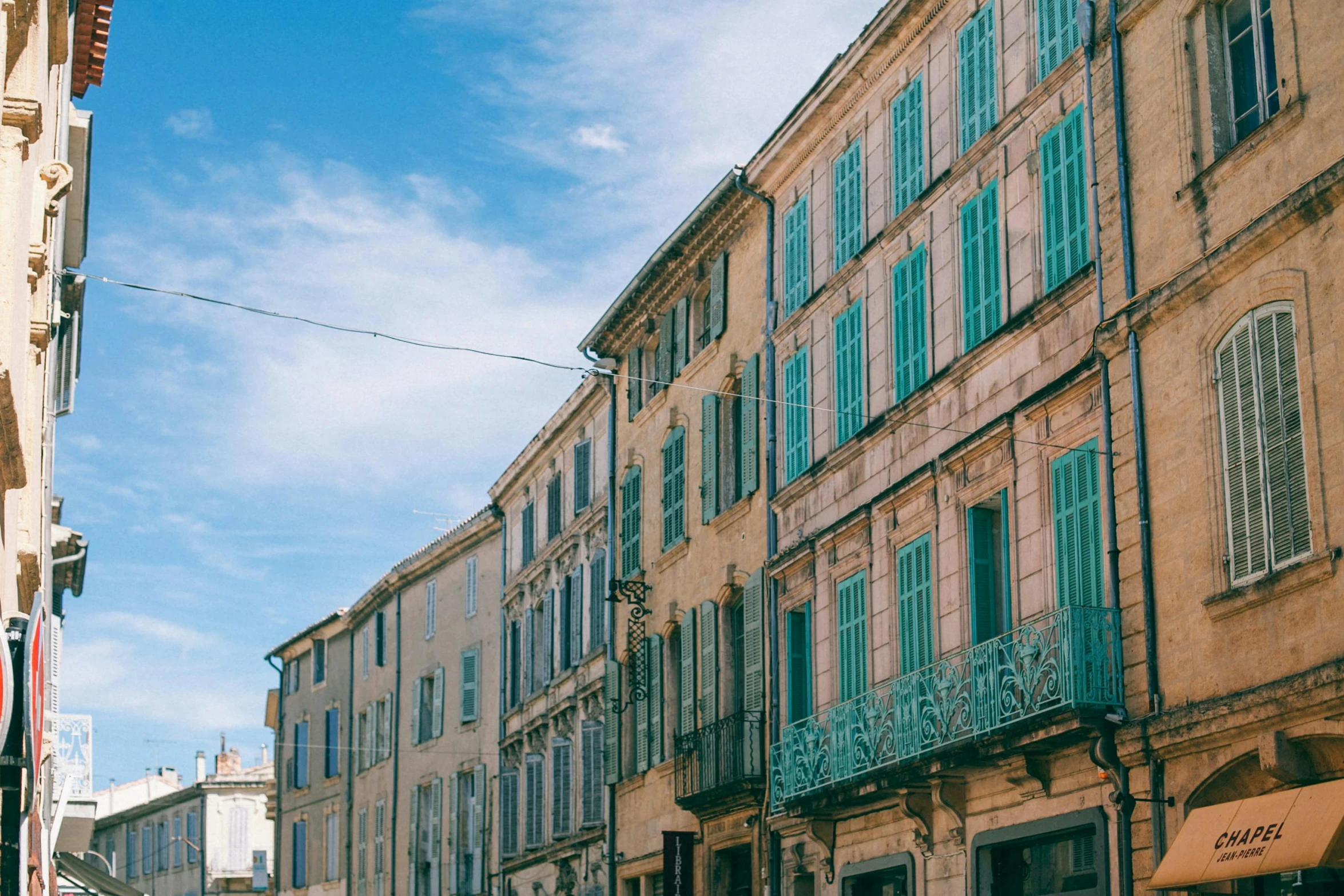 a group of people walking down a street next to tall buildings, pexels contest winner, neoclassicism, cyan shutters on windows, french village exterior, square, an abandoned old