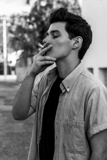 a black and white photo of a man smoking a cigarette, inspired by Jean Malouel, peter parker, 15081959 21121991 01012000 4k, beautiful boy, in sao paulo