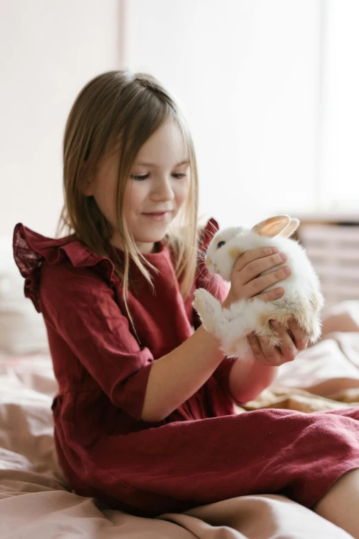 a little girl sitting on a bed holding a bunny, thumbnail, essence, pet animal, premium quality