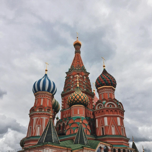 a group of people standing in front of a building, inspired by Vasily Surikov, pexels contest winner, black domes and spires, brown red blue, instagram post, view from ground