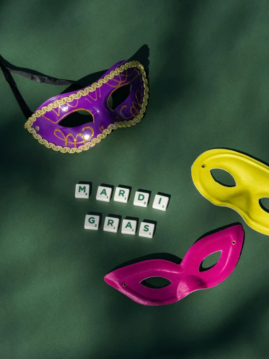 a couple of mardi gras masks laying on top of each other, a photo, trending on pexels, board game cover art, squares, ((purple)), detailed product image