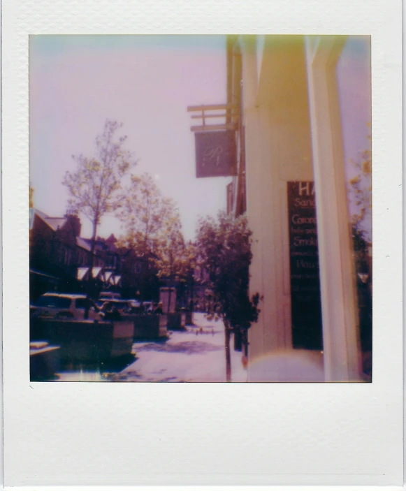 a polaroid picture of a building with a clock on it, old shops, iridescent aesthetic, esher, lots of sunlight