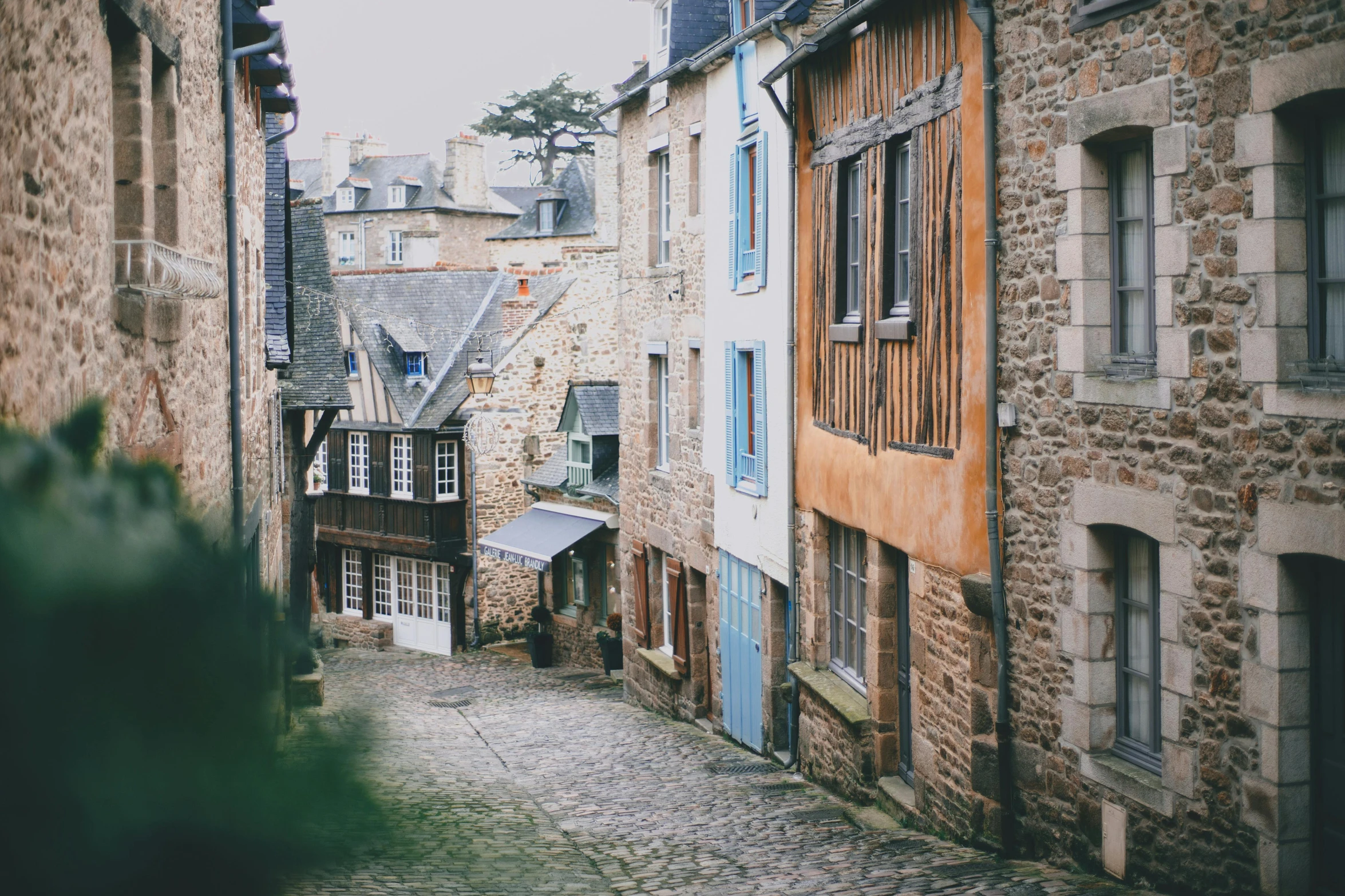 a narrow cobblestone street lined with old buildings, inspired by Jeanne du Maurier, pexels contest winner, medieval coastal village, vibrant but dreary gold, rennes - le - chateau, 90's photo