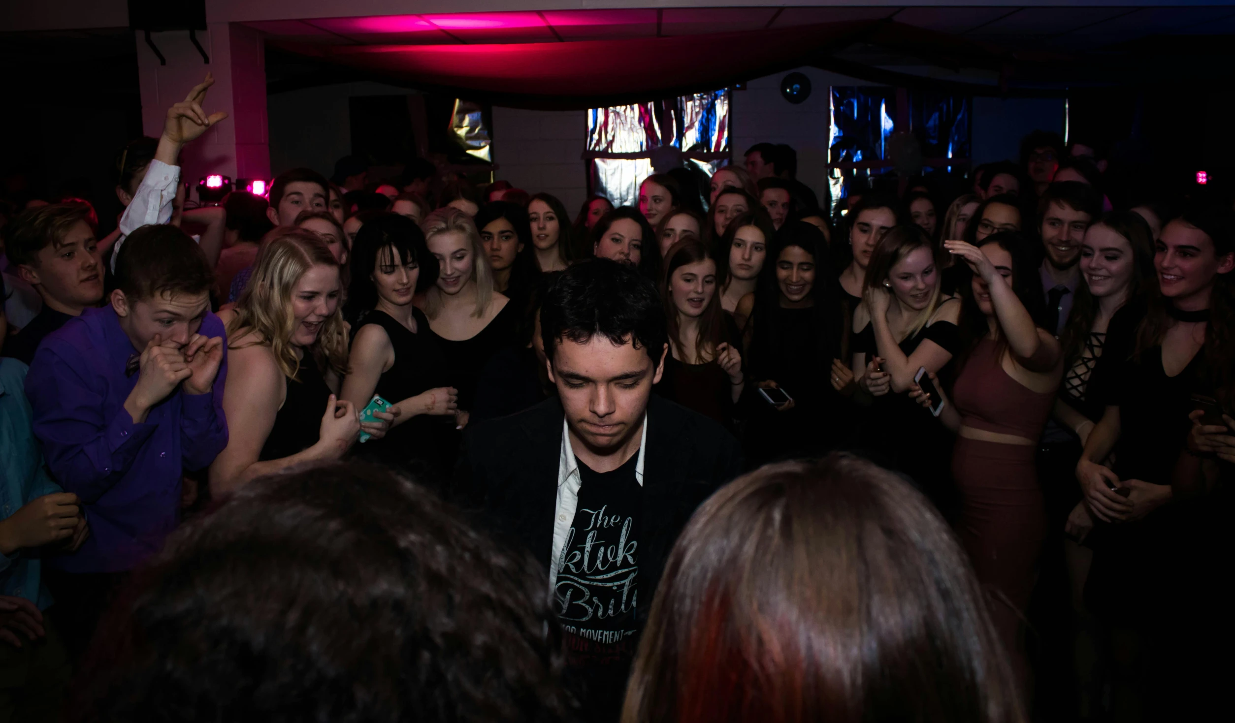 a man standing in front of a crowd of people, an album cover, by Dicky Doyle, pexels contest winner, happening, in a nightclub, robert sheehan, facing the camera, schools