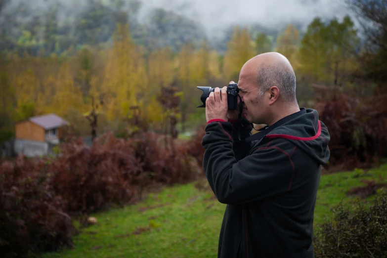 a man taking a picture with a camera, a picture, inspired by Steve McCurry, pexels contest winner, in front of a forest background, autumn, romanian, profile picture 1024px