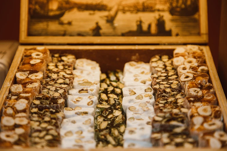 a box filled with lots of pastries sitting on top of a table, a picture, by Julia Pishtar, trending on pexels, hurufiyya, gold and white robes, istanbul, in a row, 1792