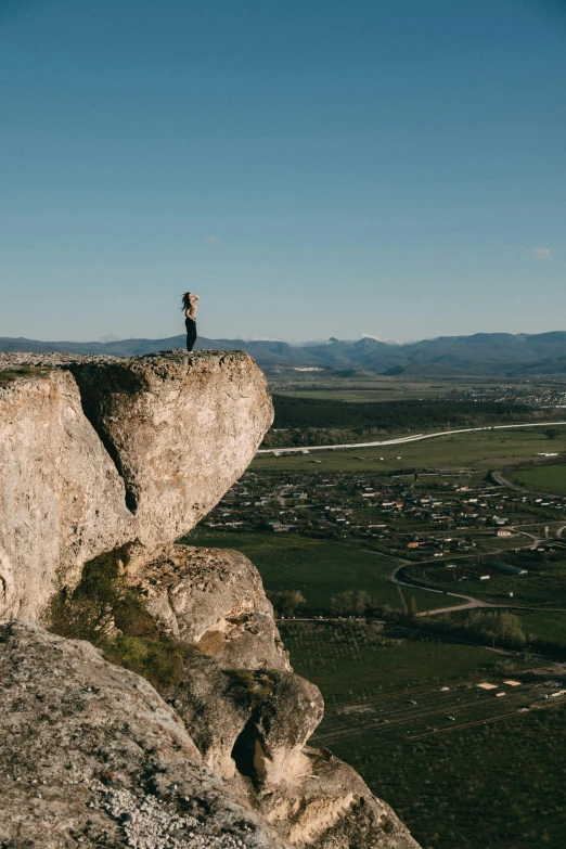 a person standing on top of a large rock, by Peter Churcher, 4k panoramic, surrounding the city, amanda lilleston, traverse