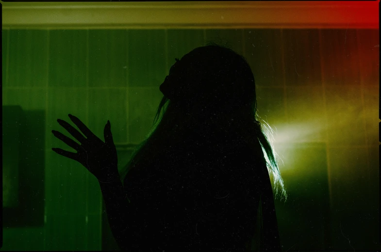 a silhouette of a woman in a dark room, an album cover, inspired by Elsa Bleda, green scary lights, repulsion, photographed on colour film, waving