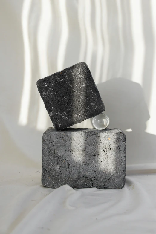 a piece of concrete sitting on top of a block, an abstract sculpture, unsplash, crystal cubism, charcoal skin, energy spheres, product shot, with a square