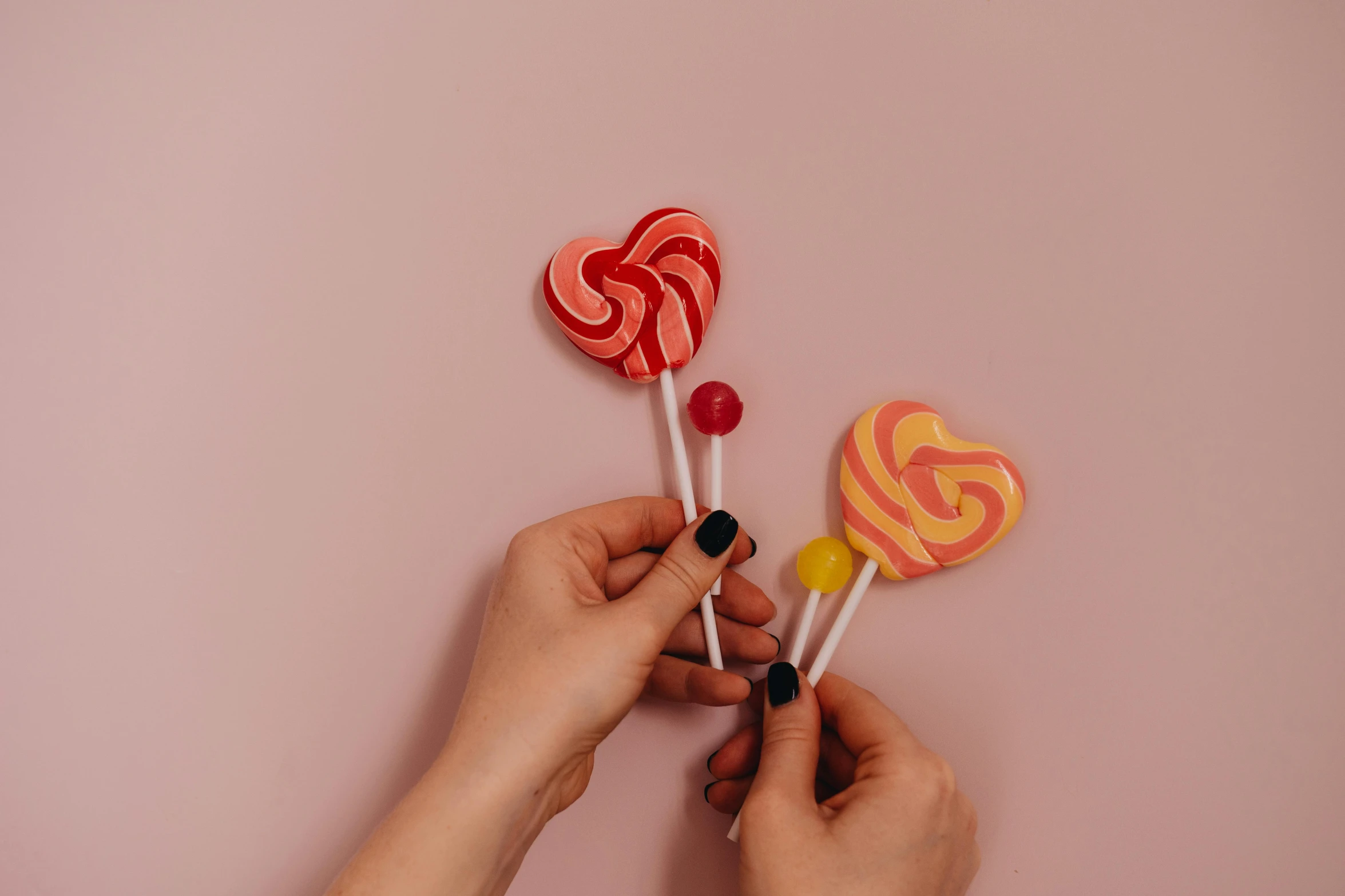 a person holding three lollipops in their hands, inspired by Ödön Márffy, trending on pexels, pink and yellow, hearts symbol, flat lay, jelly