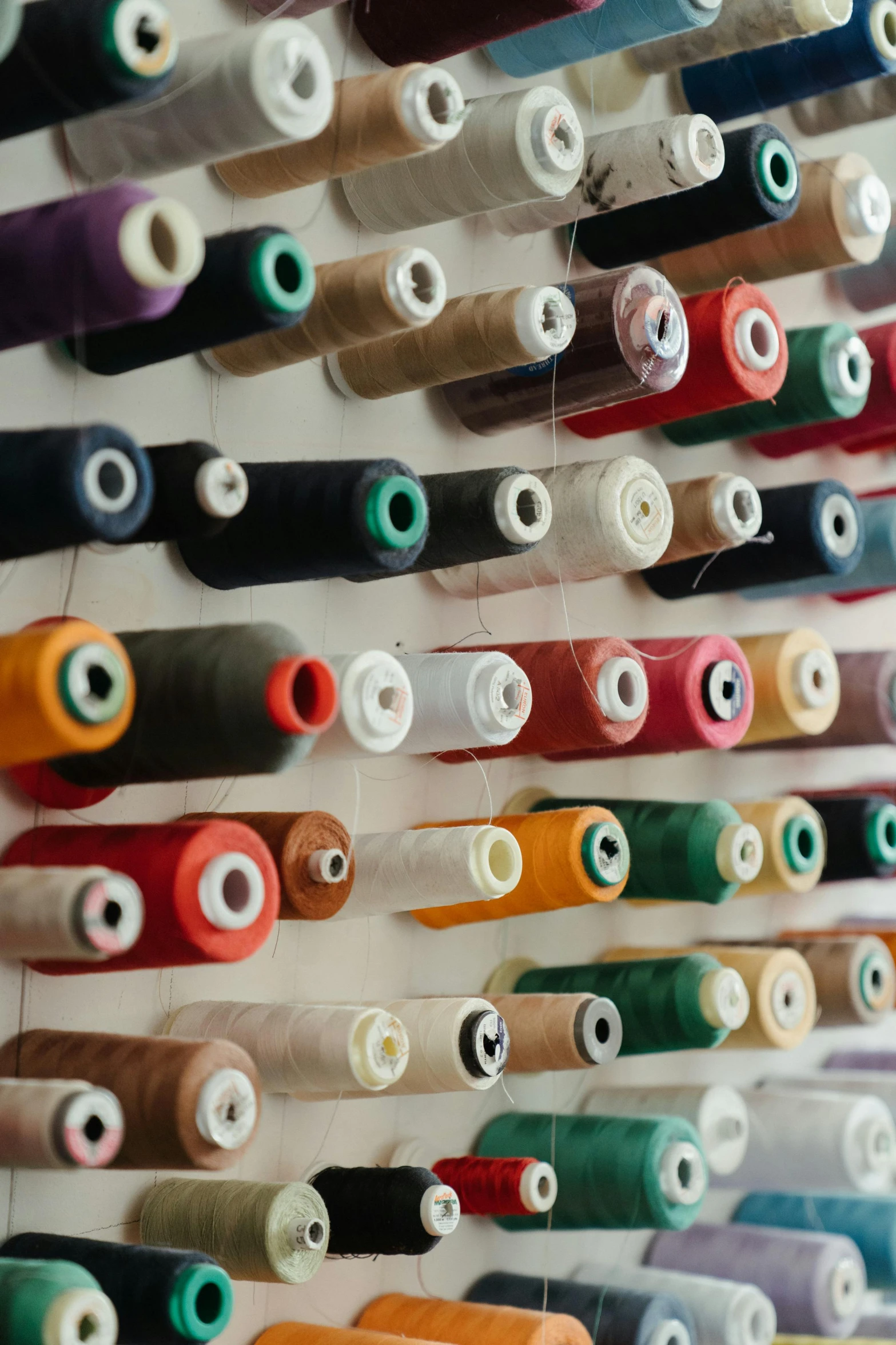 a bunch of spools of thread hanging on a wall, slide show, multiple stories, up-close, multiple colors