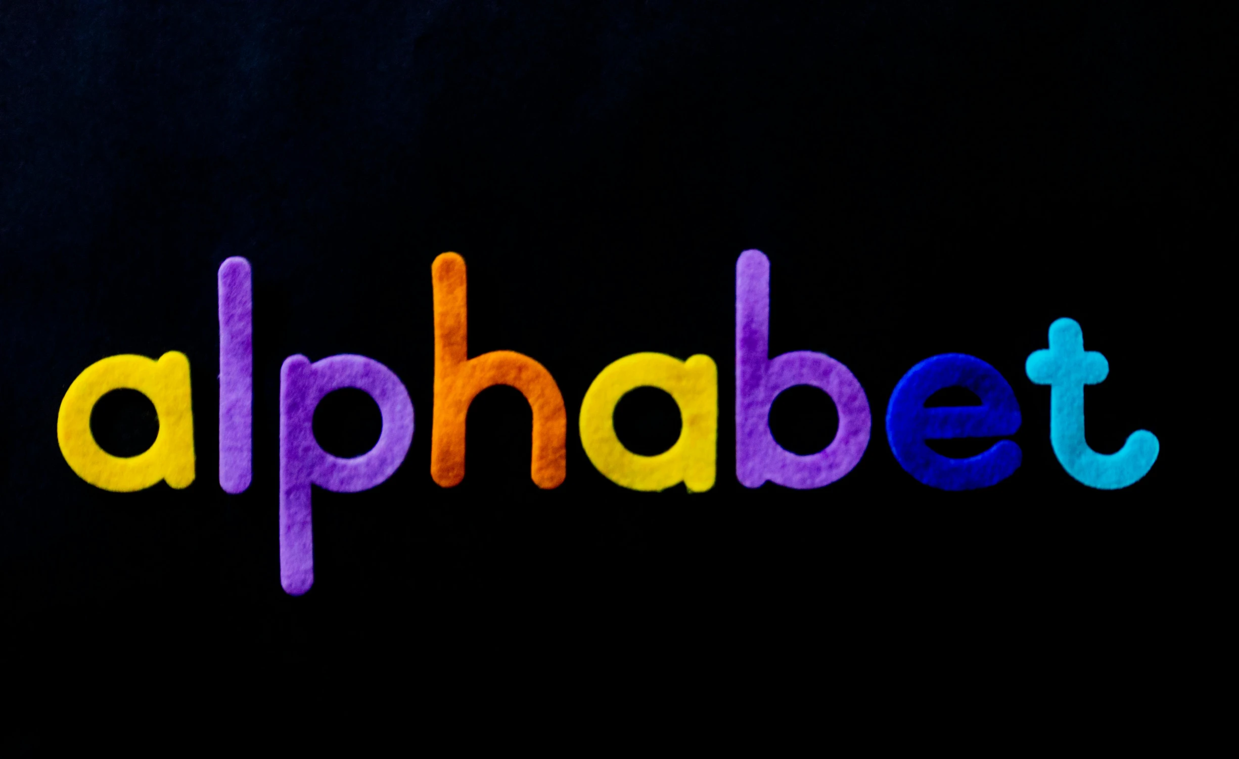 a close up of the word alphabet on a black background, unsplash, cute colorful adorable, purple and yellow, philip k d, red blue purple black fade