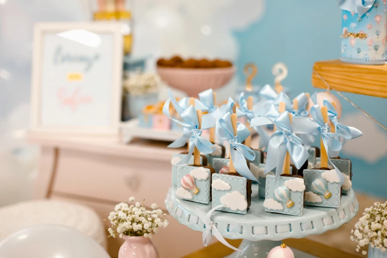 a table that has a bunch of cupcakes on it, by Emma Andijewska, pexels contest winner, sky blue and white color scheme, ribbon, miniature product photo, puffy cute clouds