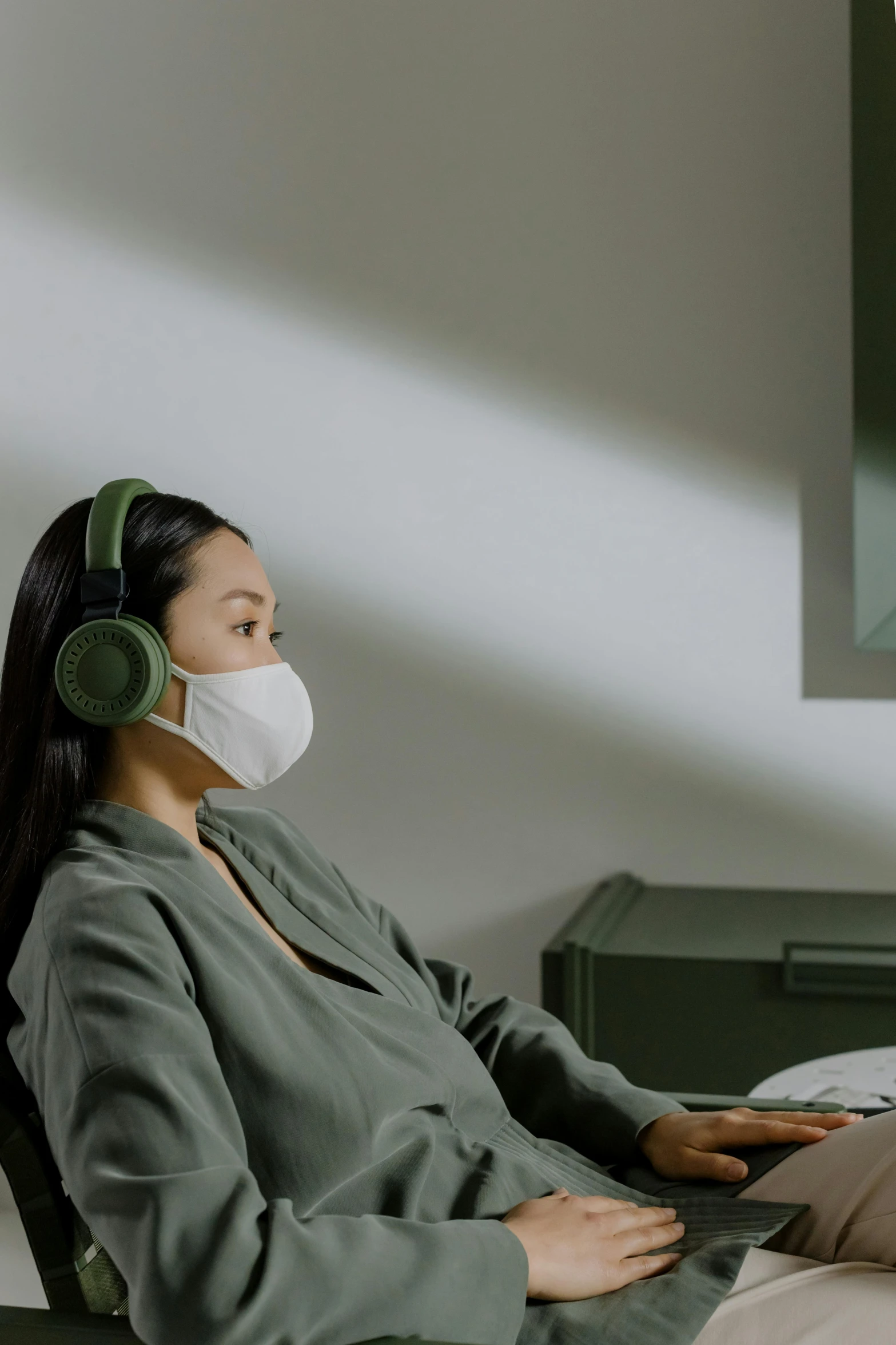 a woman sitting in a chair with a laptop wearing a face mask, inspired by Fei Danxu, purism, wearing modern headphone, forest green, high clarity, hifi